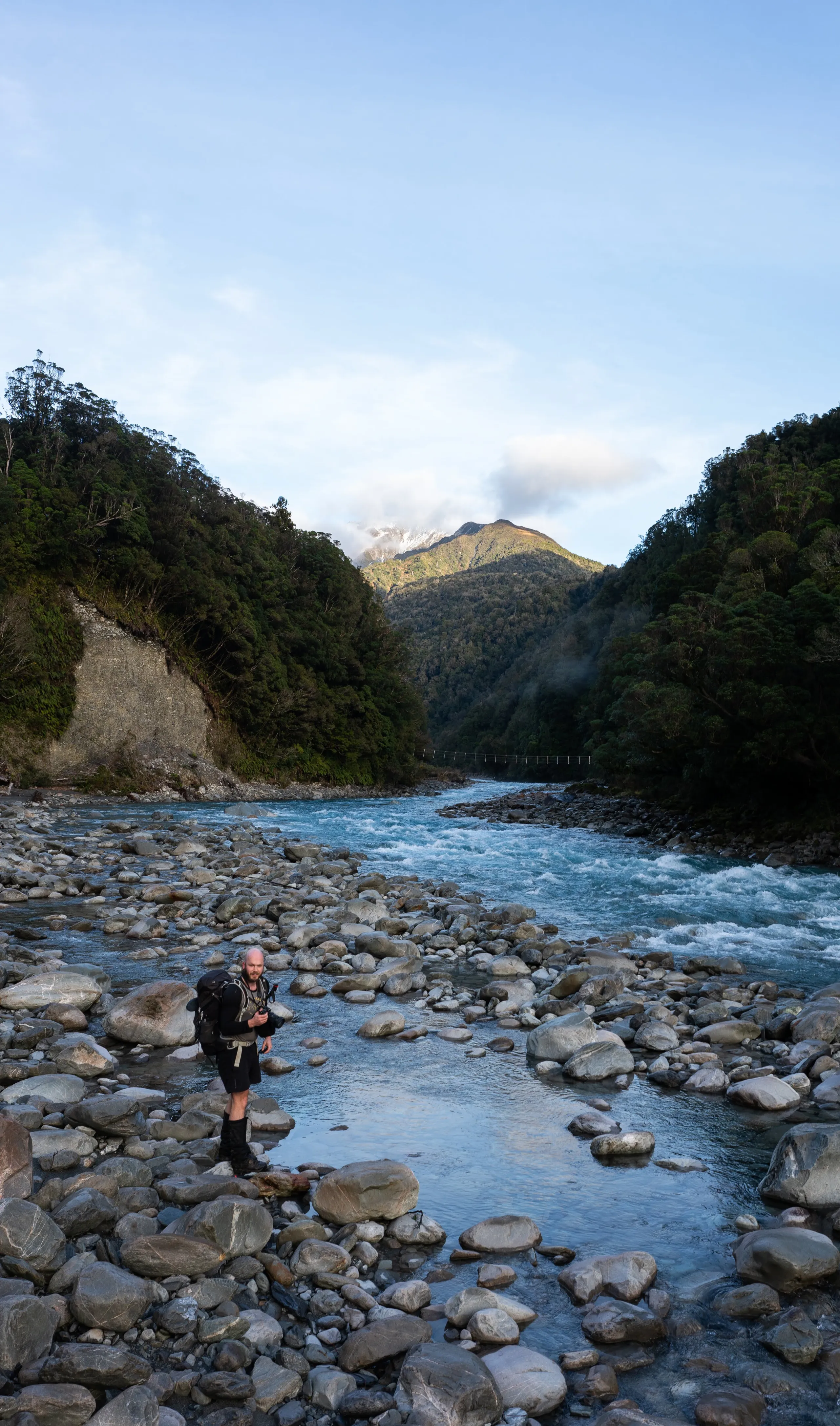 Lining up a photo spot beside the river. The azure blue colour of the river was striking. The three-wire bridge can be seen in the distance.